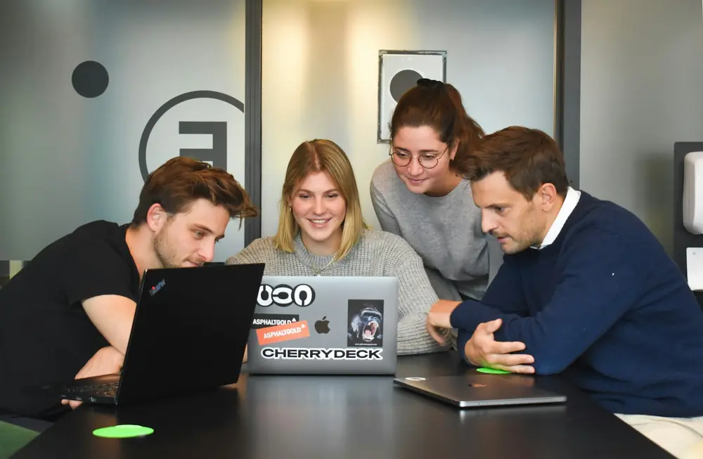 Dept Marketing Marketing team collaborating around a laptop