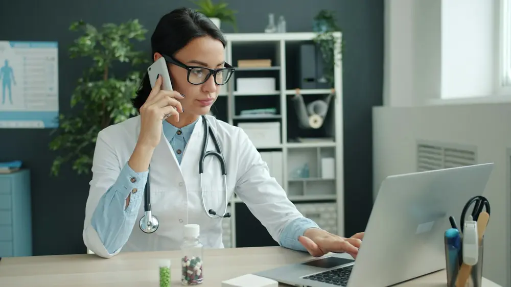 Ind Health Healthcare administrator on the phone at a laptop
